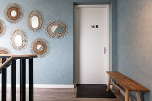 A hallway with a wooden bench, a door labeled "15 K", and wall-mounted mirrors.