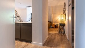 Una cocina moderna con armarios oscuros, piso de madera y un área de comedor con una lámpara y cojines.