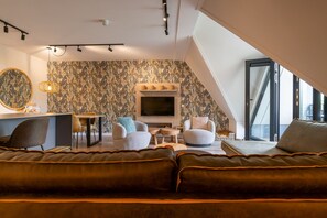 A modern living room with a sofa, chairs, a TV, and a patterned wall.