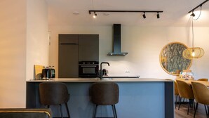 Una cocina moderna con una isla central, taburetes de bar y una zona de comedor con una mesa redonda y sillas.