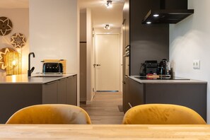 A modern kitchen with a toaster, coffee maker, and kettle on the counter. - Apartment with sauna near the sea in Oostkapelle | Duno Lodge (Oostkapelle)