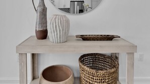 Een houten console tafel met een ronde spiegel erboven, waarop een keuken in de weerspiegeling te zien is.
