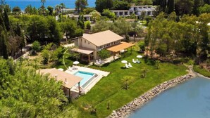 A large house with a swimming pool, surrounded by lush greenery and a view of the sea. - Beachfront villa 100 metres from the sandy beach (Kontokálion)
