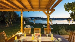 An outdoor dining area with a table set for two, overlooking a body of water and a distant cityscape. - Beachfront villa 100 metres from the sandy beach (Kontokálion)