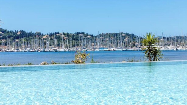 A clear blue pool with a view of a marina and a hillside in the background. - Beachfront villa 100 metres from the sandy beach (Kontokálion)