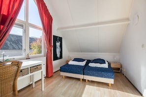Een slaapkamer met een bed, een bureau en een raam.