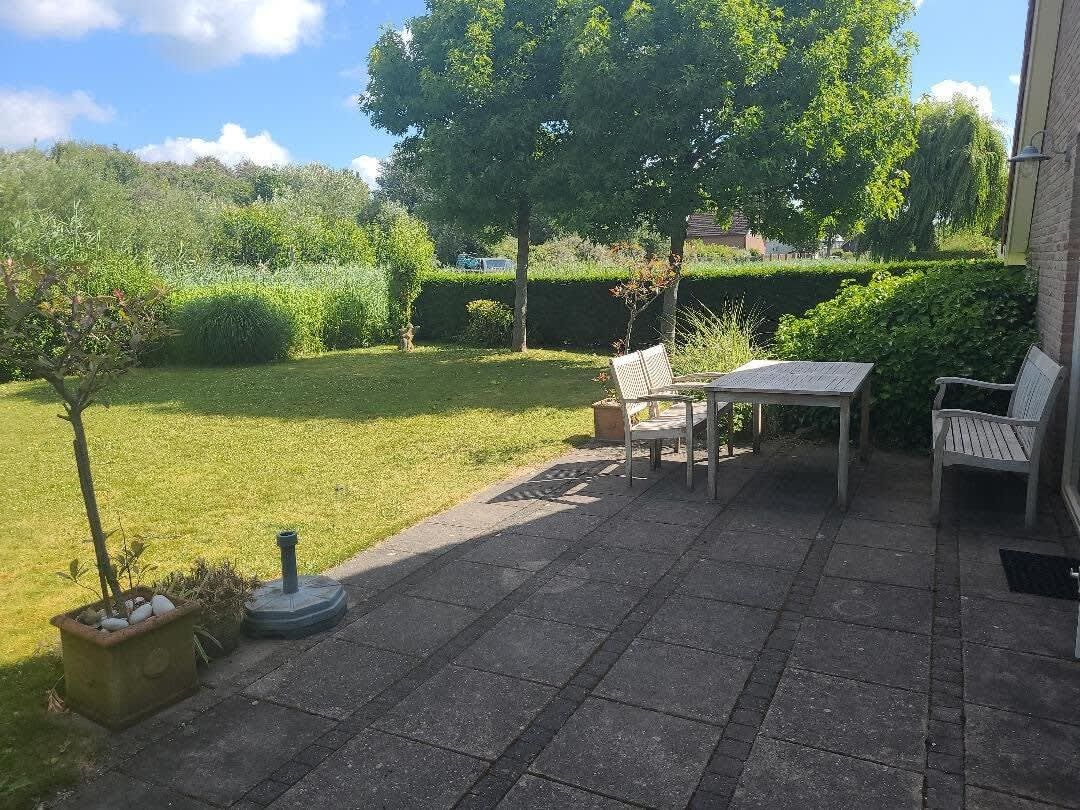 A patio with a table and two chairs, a small tree, and a well-maintained lawn.