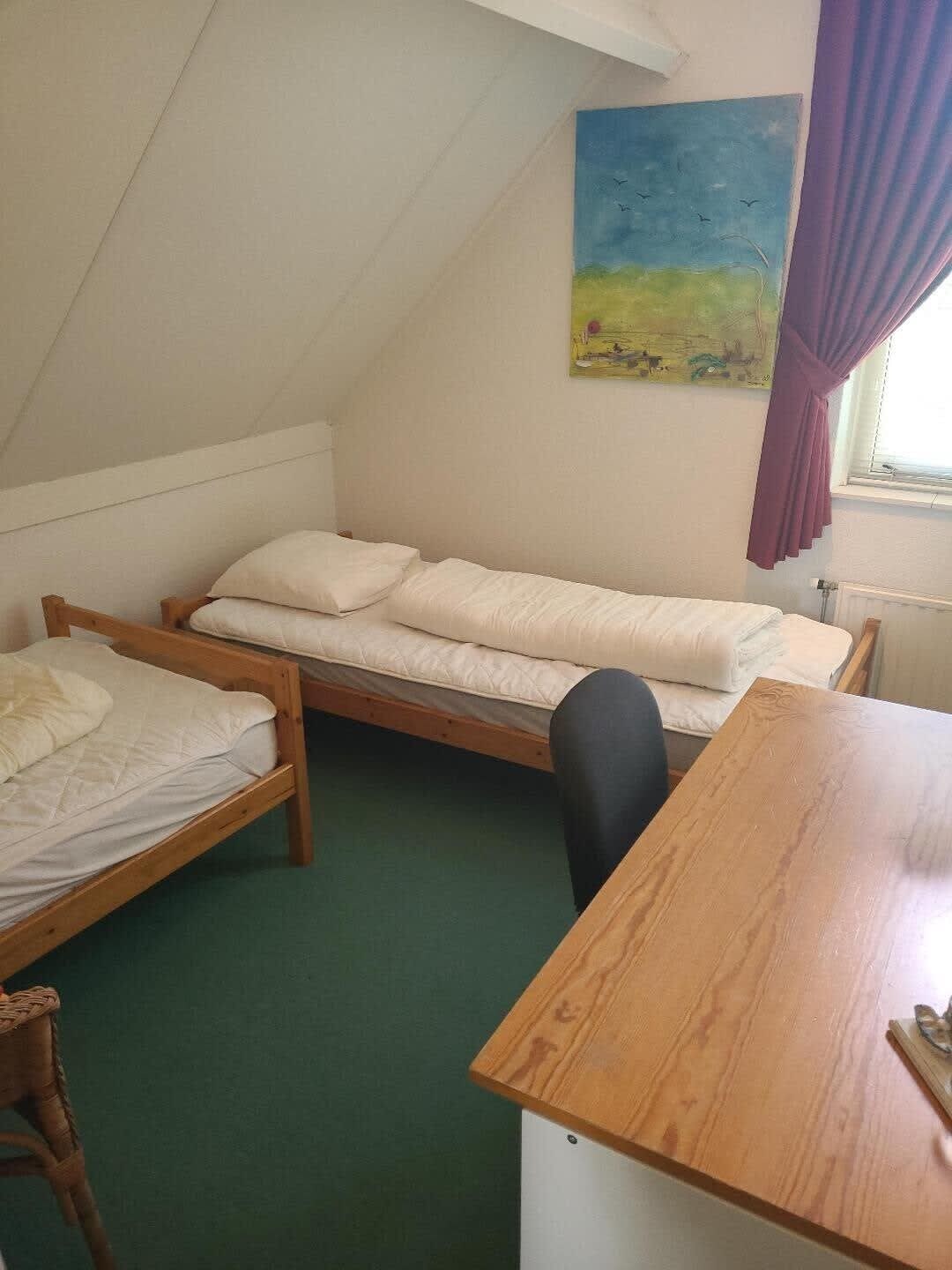 Quarto em dormitório com duas camas de beliche, uma escrivaninha de madeira e um quadro na parede.