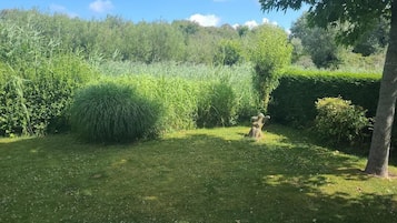 Ein gepflegter Garten mit vielfältigen Pflanzen und einer Steinskulptur.