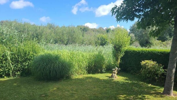 Ein gepflegter Garten mit vielfältigen Pflanzen und einer Steinskulptur.