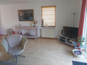 Ein Wohnzimmer mit Sofa, Fernseher, Heizkörper und einem Bild an der Wand.