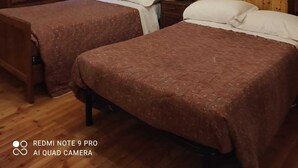 Une pièce chaleureuse aux murs et au plafond en bois, avec deux lits dotés de draps bruns, une commode en bois et un miroir accroché au mur.