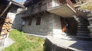 Un bâtiment en pierre doté d’un balcon en bois et d’un escalier menant à un niveau supérieur.