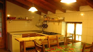 Une cuisine avec des meubles de rangement en bois, une cuisinière et une table à manger avec des chaises.