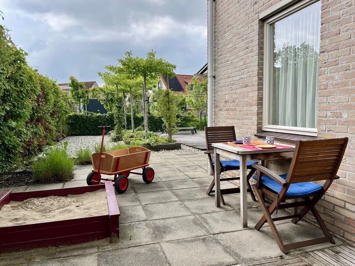 A patio with a table and chairs, a wooden cart, and a brick wall.