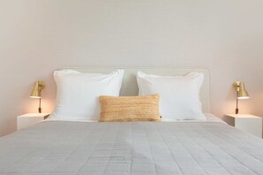 A neatly made bed with white linens and a textured pillow, flanked by two bedside tables with lamps. - Studio with AC in Domburg | Summum Suites 4 (Domburg)