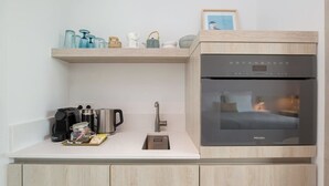 Una kitchenette compacta con horno integrado, cafetera y lavamanos.