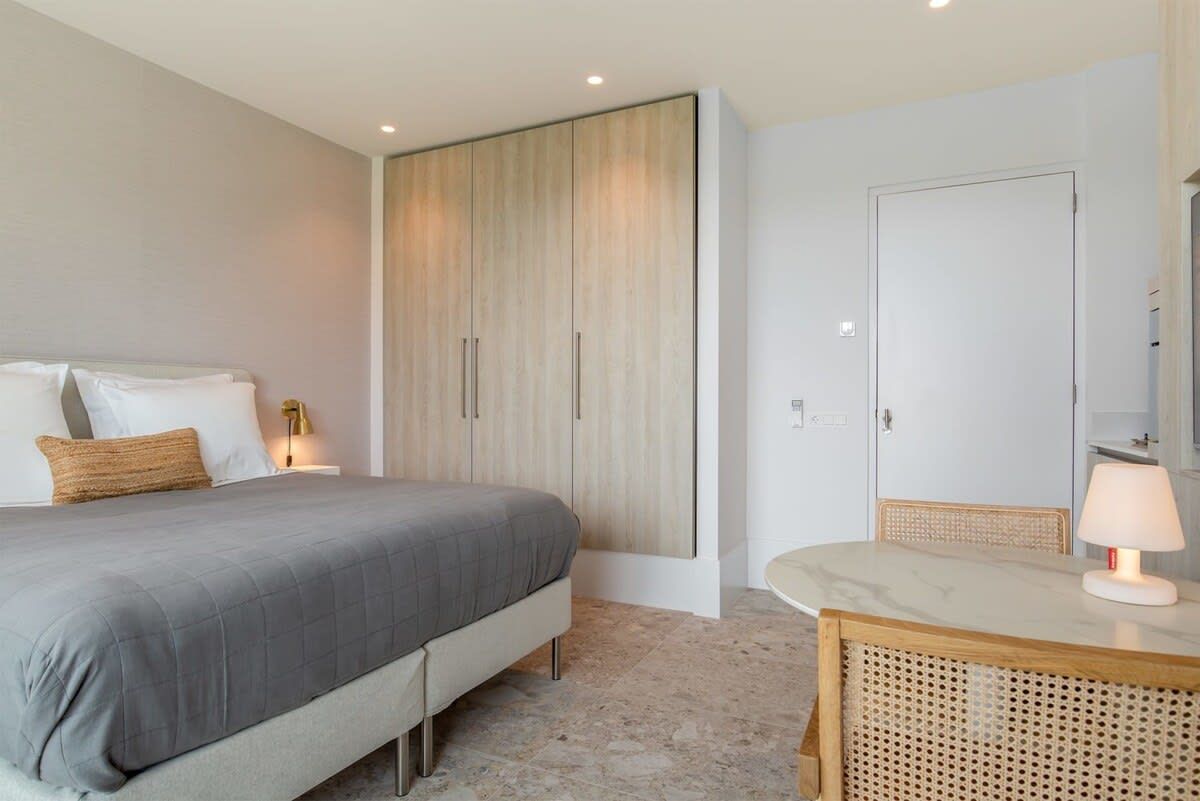 Ein Schlafzimmer mit Bett, Nachttisch, Lampe und Kleiderschrank.