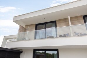 A modern two-story building with a balcony featuring outdoor seating. - Studio with AC in Domburg | Summum Suites 4 (Domburg)