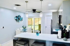 Una cocina moderna con una isla central, luces colgantes y un ventilador de techo.