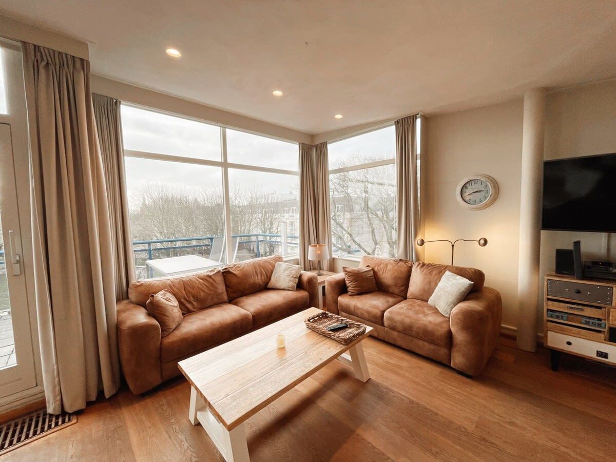 Un salon moderne avec un canapé d’angle, une table basse en bois et un téléviseur posé sur un meuble.