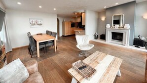 A modern living room with a wooden dining table, a sofa, and a fireplace. - Penthouse near the beach in Domburg | Park Loverendale 31 (Domburg)