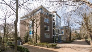 A modern multi-story residential building with a brick facade, large windows, and a blue entrance door. - Penthouse near the beach in Domburg | Park Loverendale 31 (Domburg)