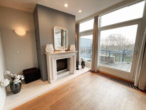 A modern living room with a fireplace, a large window, and a view of the outdoors.