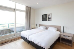 A modern bedroom with a large bed, two bedside tables, and a window with a view.