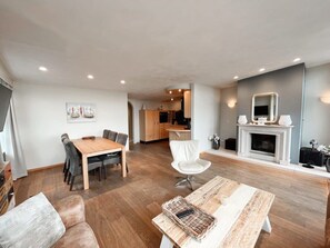 A modern living room with a wooden dining table, a sofa, and a fireplace.