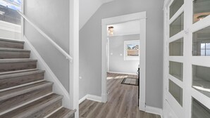 Uma escadaria leva a um quarto com vista, uma porta com painéis de vidro e um lustre acima da porta.