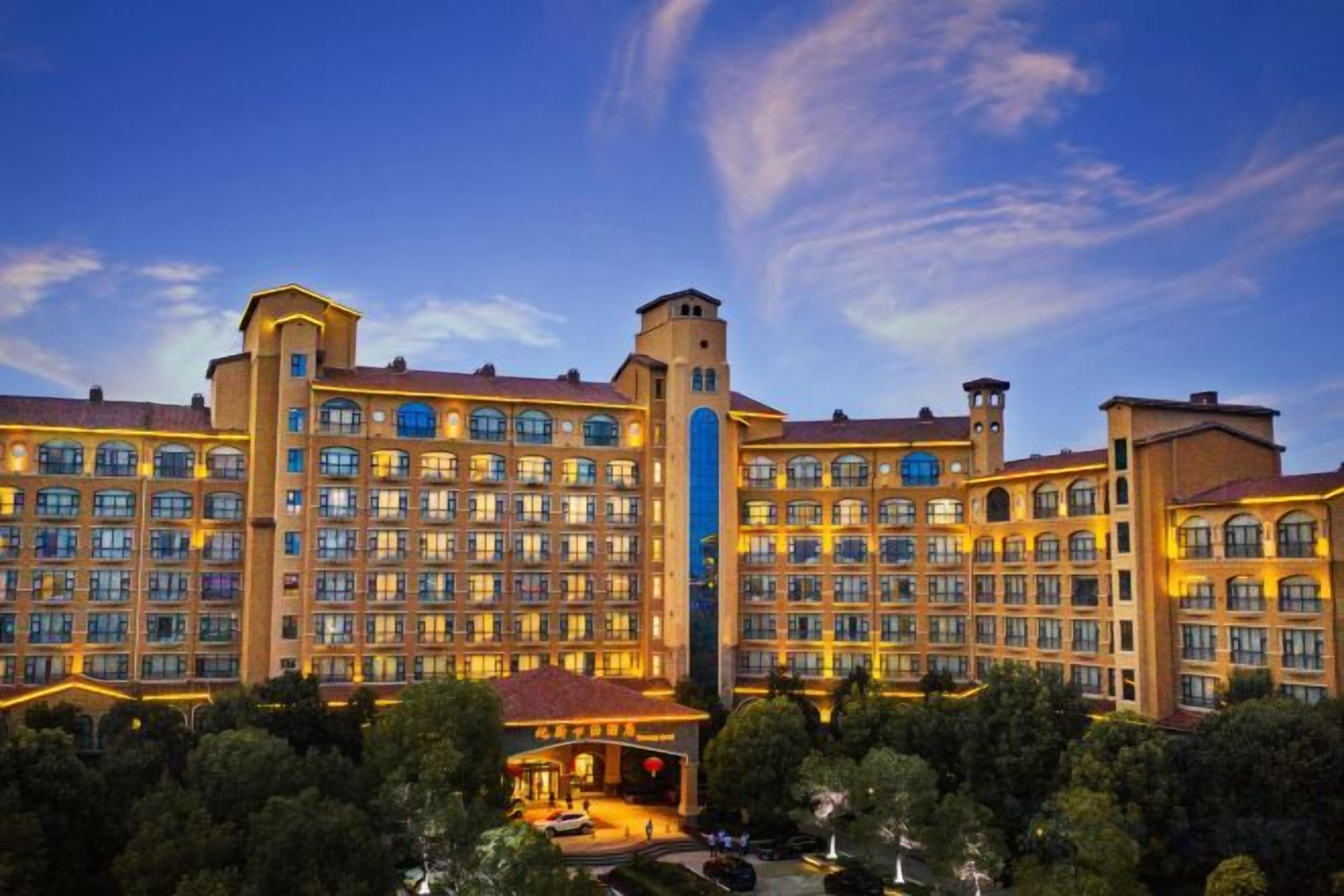 A large hotel with multiple floors, a central tower, and a well-lit facade.