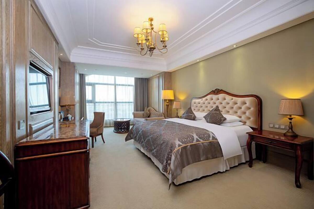 Una habitación de hotel con una cama grande, un escritorio, una silla, una lámpara y un candelabro.