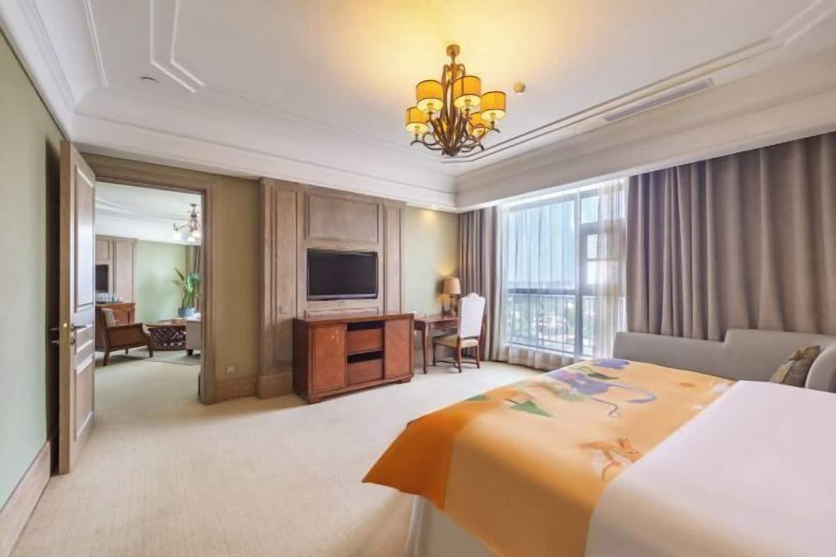 Una habitación de hotel con una cama, televisión, escritorio y una silla.