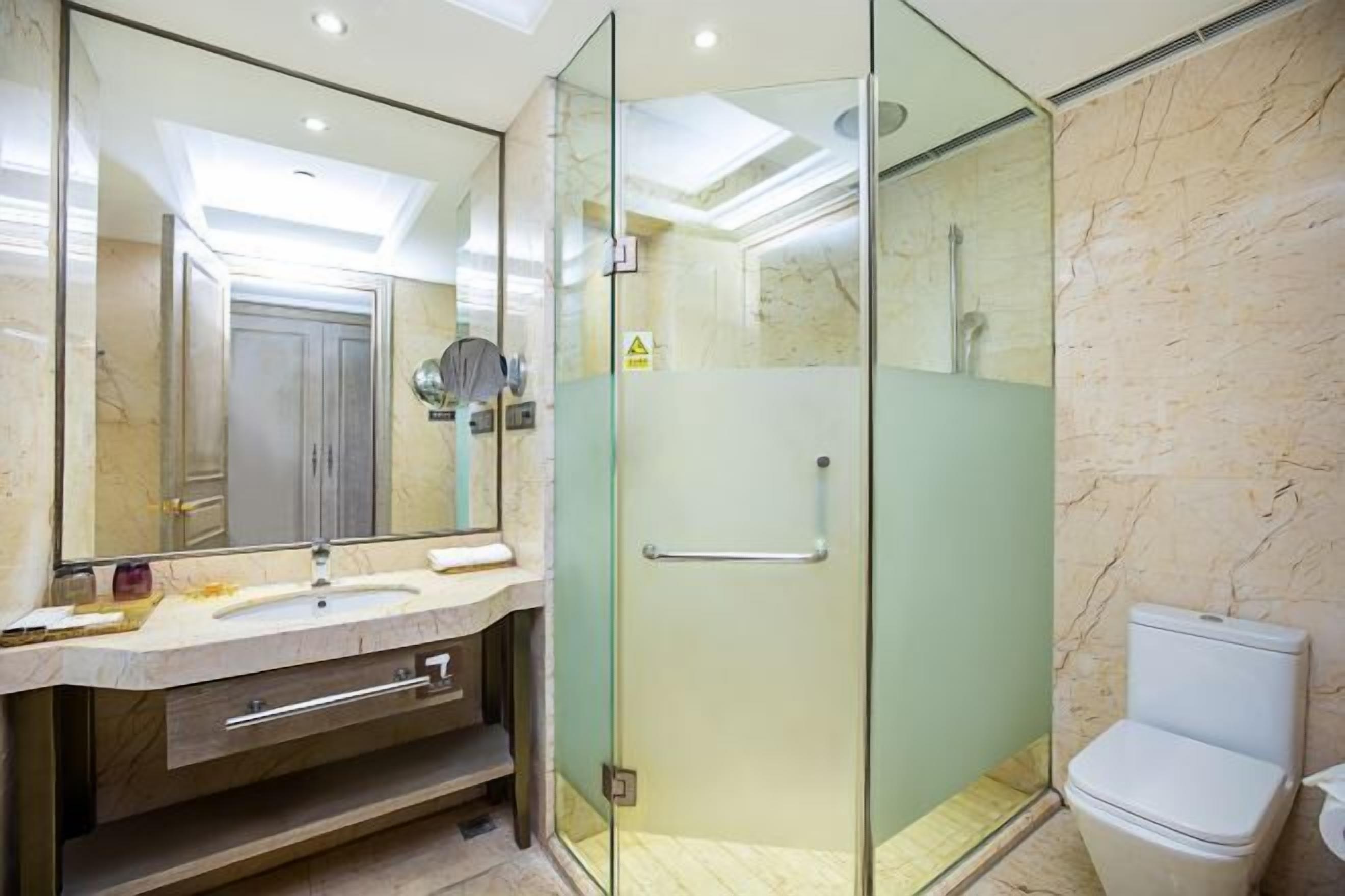 Un bagno moderno con doccia vetrata, uno specchio ampio e un pavimento in marmo.