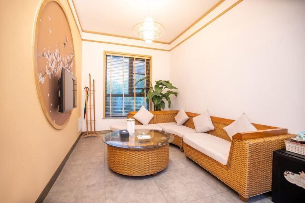 A living room with a wicker sofa, a glass coffee table, and a large mirror on the wall.