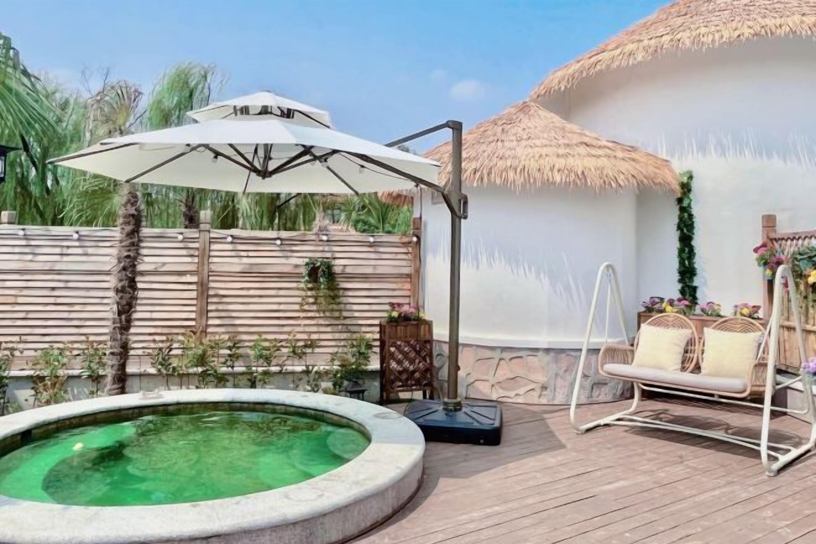 A pool with a white umbrella, a swing chair, and a thatched-roof structure. - Yanling Bloom Hot Spring Hotel (Yanling)