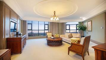 A spacious living room with a large window, a round coffee table, a sofa, and a wooden cabinet.