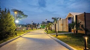 A pathway leading to a building with a modern design, surrounded by well-maintained grass and trees, and illuminated by street lamps. - Yanling Bloom Hot Spring Hotel (Yanling)