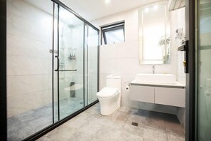 A modern bathroom with a glass shower enclosure, a white toilet, and a sink with a mirror above it. - Yanling Bloom Hot Spring Hotel (Yanling)