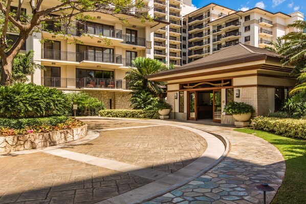 A hotel entrance with a curved driveway, surrounded by lush greenery and a stone pathway. - Hale Papakea Ko Olina Beachfront Villa w/ Views (Kapolei)