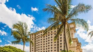 Un hotel con un edificio grande, una cascada y palmeras.