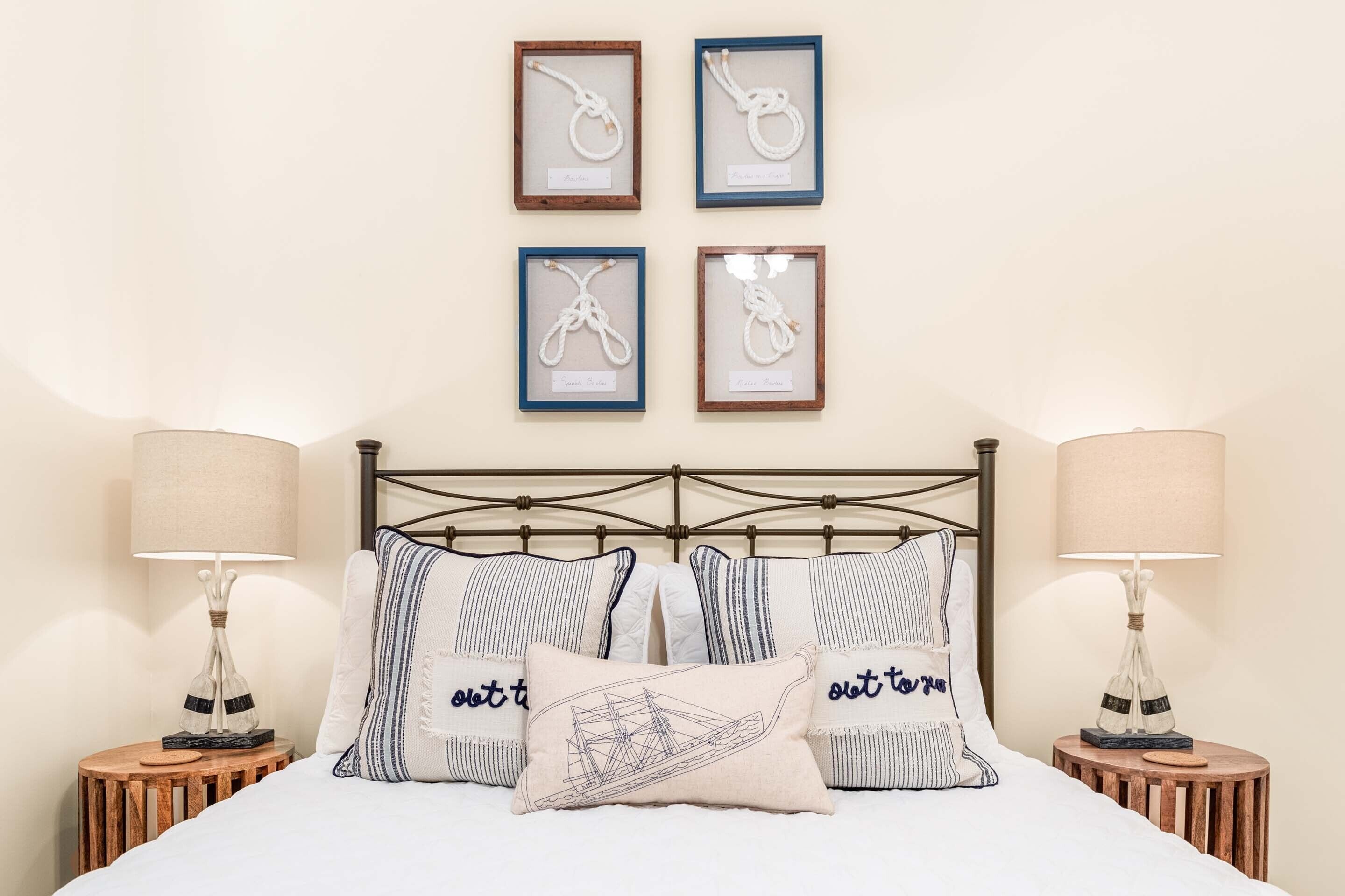 A neatly arranged bedroom with a bed, two bedside tables, and four framed artworks on the wall.