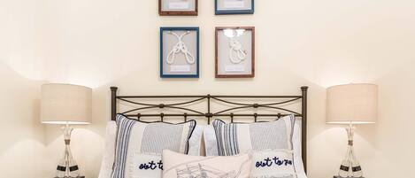 A neatly arranged bedroom with a bed, two bedside tables, and four framed artworks on the wall.