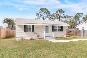 A single-story house with a front porch, a small front yard, and a wooden fence. - Bowline Bungalow Tybee Vacation Rentals (Tybee Island)