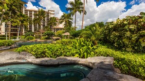 Un resort con piscina, palmeras y un edificio grande al fondo.