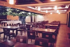 Un restaurante con varias mesas y sillas, un árbol grande y una barra.