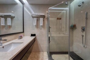 Une salle de bain moderne avec une douche à parois de verre, un grand miroir et un comptoir en marbre.