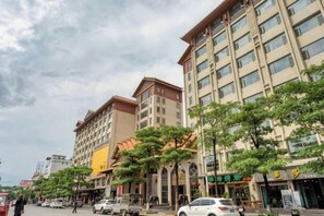 A multi-story hotel with a traditional architectural style, featuring a central courtyard with trees and a covered walkway. - Bianchui Hotel (Yingjiang)