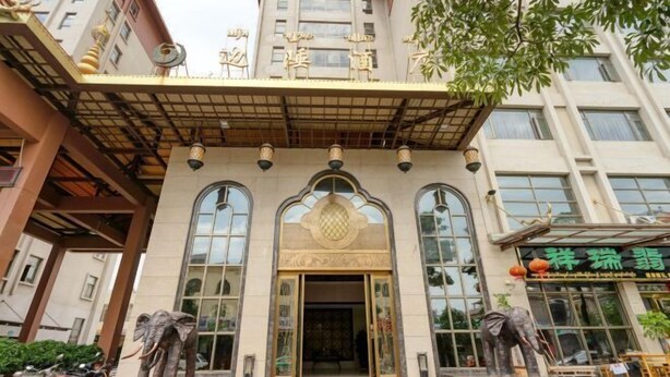 A building with a traditional architectural style, featuring a central entrance with a decorative archway and two elephant statues on either side. - Bianchui Hotel (Yingjiang)